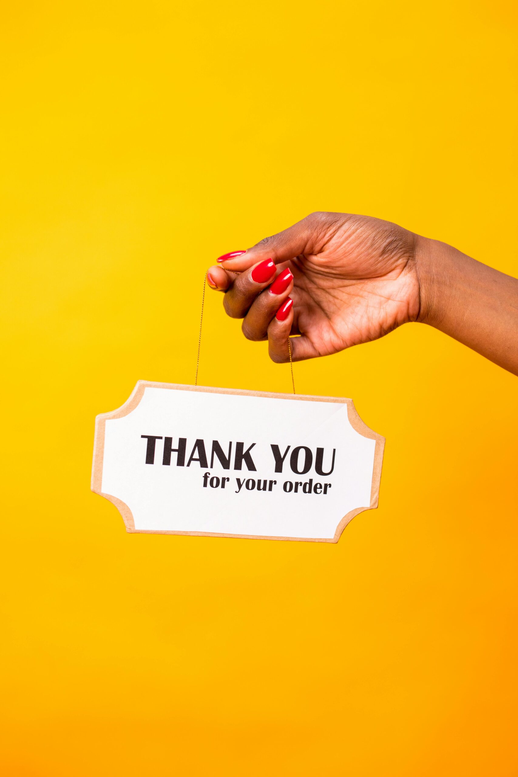 user3-free-img A hand holds a 'Thank You for Your Order' sign against a vibrant yellow background.